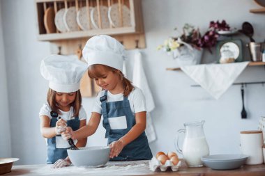 Beyaz şef üniformalı aile çocukları mutfakta yemek hazırlıyorlar..