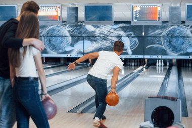 Turuncu renkli top. Genç neşeli arkadaşlar hafta sonları bowling kulübünde eğleniyorlar..