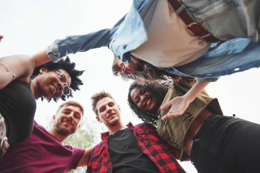 Birbirinize sarılın. Çok ırklı bir grup insan dışarıda parti veriyor. Aşağıdan görüntüle.