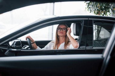 Uzaklara bakıyorum. Yeni arabasında oturan güzel sarışın kız..