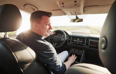 Sürücü yeni arabasında iyi hissediyor. Güneşli bir günde at sürmek.