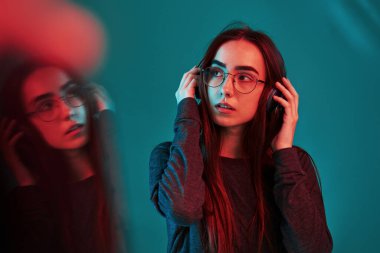 Cam kullanarak yansıtma efekti. Stüdyo içeride neon ışıkla çekiliyor. Güzel bir genç kızın portresi.