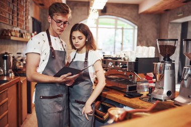 Not defteriyle. Birbirleriyle konuşuyorlar. İki genç kafe çalışanı içeride. İş ve hizmet kavramı.
