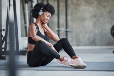 Keyfin yerinde. Kıvırcık saçlı ve spor elbiseli Afrikalı Amerikalı kadın spor salonunda spor yapıyor..