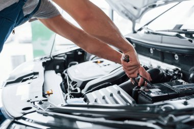 Bunun şarj edilmesi gerekiyor. Kazadan sonra araba tamir işlemi. Motor kaputunun altında çalışan bir adam..