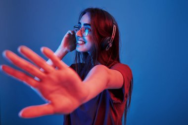 Eğleniyorum. Stüdyo içeride neon ışıkla çekiliyor. Güzel bir genç kızın portresi.