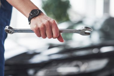 Arka plan bulanık. Kadın tamirci kendi işini yapıyor. Araba dükkanında kapalı..