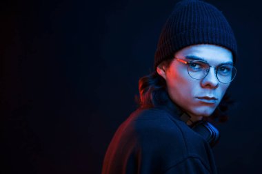 Modaya uygun bir adam. Stüdyo karanlık stüdyoda neon ışıkla çekiliyor. Ciddi bir adamın portresi..