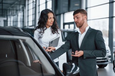 Profesyonellerin görüşü. Kadın müşteri ve modern stil sahibi sakallı iş adamı otomobil barında..