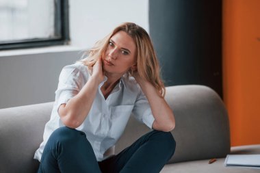 İşten sonra. Kıvırcık sarı saçlı iş kadını pencerenin karşısında oturuyor..