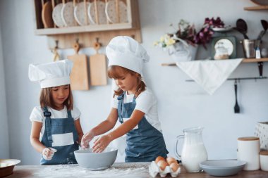 Beyaz şef üniformalı aile çocukları mutfakta yemek hazırlıyorlar..