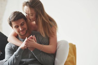 Yakınlık ve sevgi. Mutlu çift yeni evlerinin oturma odasındaki sarı kanepede dinleniyor..