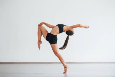 Çılgınca numaralar yapıyor. Siyah elbiseli, zayıf vücutlu genç, sportif bir kadın. Sağlık merkezinde egzersiz yapıyor..