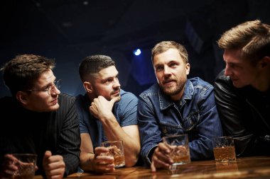 Ön manzara. Arkadaşlar ellerinde alkolle barda dinleniyorlar. Sohbet ederken.