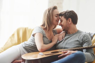 En sevdiğim şarkıyı çal. Gitar bacaklarda. Mutlu çift yeni evlerinin oturma odasındaki sarı kanepede dinleniyor..