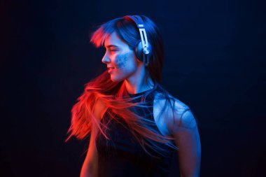 Hareketli fotoğraf. Stüdyo karanlık stüdyoda neon ışıkla çekiliyor. Genç bir kızın portresi.