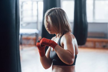 Enerji ve güç. Dişi boksör torbayı yumrukluyor. Sarışın spor salonunda egzersiz yapıyor..
