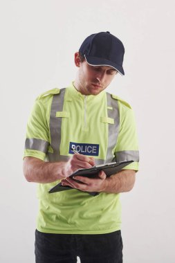 Özel ilgiye ihtiyacı olan ilişkiler. Yeşil üniformalı polis stüdyoda beyaz arka planda duruyor..