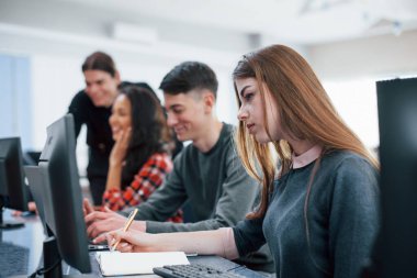 Konsantre sarışın. Modern ofiste çalışan günlük kıyafetli bir grup genç..