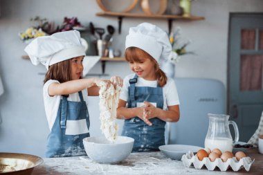 Beyaz şef üniformalı aile çocukları mutfakta yemek hazırlıyorlar..