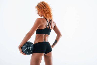 Futbol toplu bir kamera için poz vermek. Parçacık görünümü. Kızıl saçlı kadın vücut geliştirici beyaz arka planda stüdyoda..