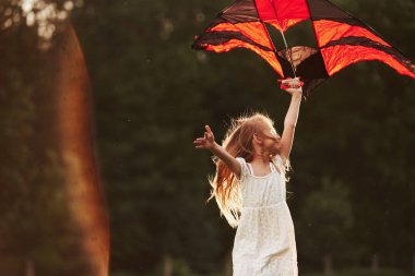 Sol tarafta güzel bir yansıma. Beyaz elbiseli mutlu kız sahada uçurtmayla eğleniyor. Güzel doğa..