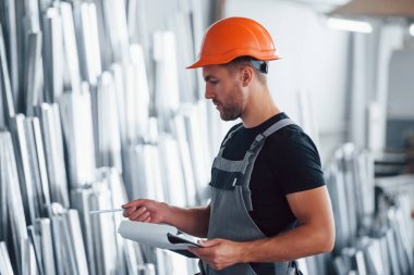 Depodaki nesneleri saymak ve kontrol etmek. Fabrikada sanayi işçisi. Turuncu şapkalı genç teknisyen..