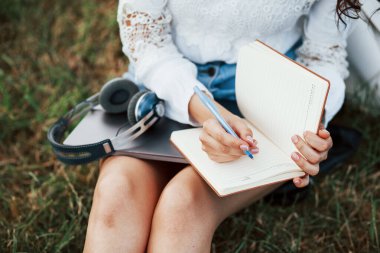 Odaklanmış fotoğraf. Genç bir kadın hafta sonu geçirir ve gündüz vakti parkta oturur..