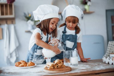 Kurabiyeler hazır. Beyaz şef üniformalı aile çocukları mutfakta yemek hazırlıyorlar..