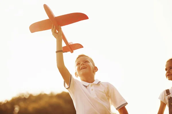 女の子と男の子楽しいです屋外でとともに赤いおもちゃの飛行機で手 — ストック写真