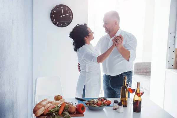 ロマンチックなディナー シニア男性と彼の妻の白いシャツの上にキッチン — ストック写真