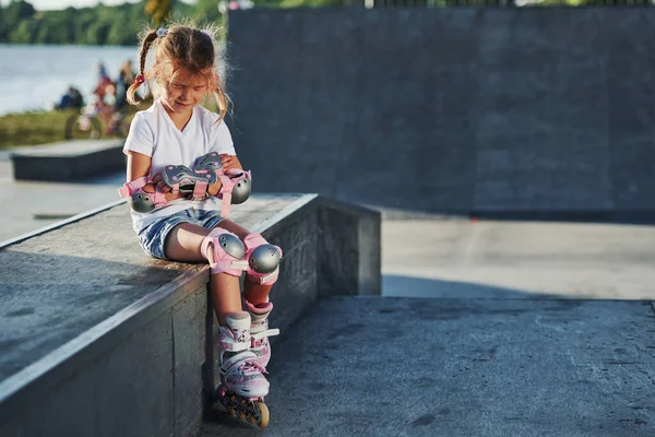 かわいいです女の子とともにローラースケート屋外で座っています極端なスポーツのためにランプ — ストック写真