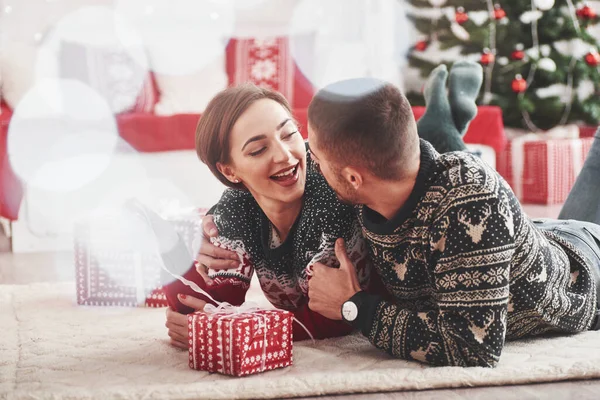 これらの休日を一緒にいることは素晴らしい 素敵な若いカップルがギフトボックスで新年のリビングルームの床に横たわっています — ストック写真