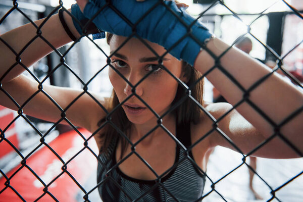 Taking a break. Sportswoman at boxing ring have exercise. Leaning on the fence.