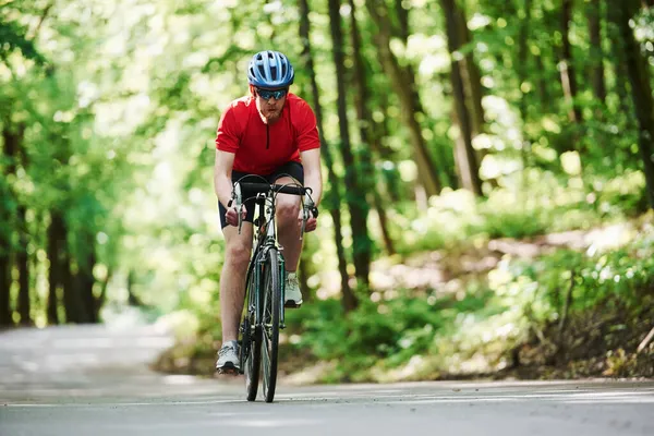 白人种族 骑自行车的人在森林里的柏油路上 — 图库照片