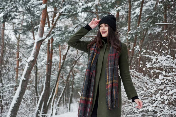 次はどこへ行こうかな 暖かい服の陽気な若い女の子は昼間に冬の森の中を散歩しています — ストック写真