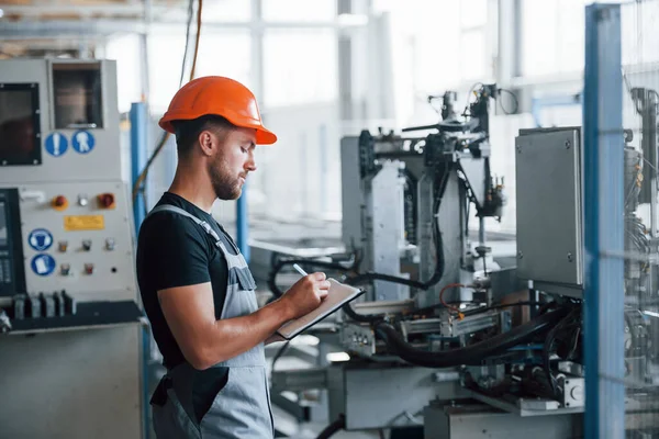 Elinde Defteriyle Fabrikada Sanayi Işçisi Turuncu Şapkalı Genç Teknisyen — Stok fotoğraf