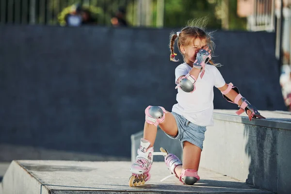 かわいいです女の子とともにローラースケート屋外で座っています極端なスポーツのためにランプ — ストック写真