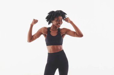 Ellerinde karın kasları var. Stüdyoda beyaz arka planda güzel bir Afro-Amerikan kadın var..