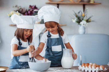 Beyaz şef üniformalı aile çocukları mutfakta yemek hazırlıyorlar..