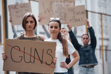 Silahlara izin vermiyoruz. Bir grup feminist kadın dışarıda hakları için protesto yapıyor..