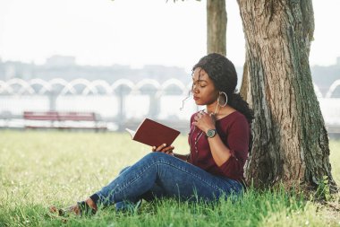 Eğitim kavramı. Yazın parktaki neşeli Afrikalı Amerikalı kadın..