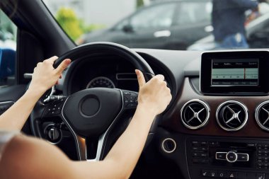 Eller direksiyonda. Modern otomobilin içindeki kadın sürücü. Yepyeni araba deneniyor.