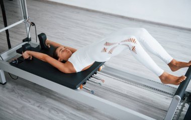 Çok çalışıyorum. Sağlıklı merkezde zayıf vücutlu, kendine güvenen genç bir kadın özel ekipman kullanarak egzersiz yapıyor..