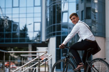 Yan görüş. Siyah bisikletli resmi giysili bir işadamı şehirde..