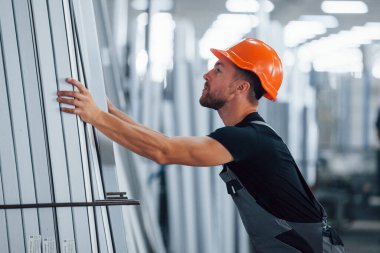 Depoda bir sürü nesneyle birlikte. Fabrikada sanayi işçisi. Turuncu şapkalı genç teknisyen..
