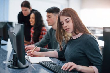 Bazı hesaplamalar yapmam gerekiyor. Modern ofiste çalışan günlük kıyafetli bir grup genç..