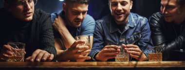 Ön manzara. Arkadaşlar ellerinde alkolle barda dinleniyorlar. Sohbet ederken.