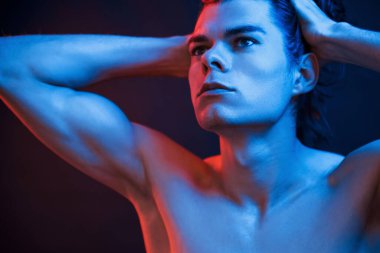 Kollar ve boyun. Stüdyo karanlık stüdyoda neon ışıkla çekiliyor. Ciddi bir adamın portresi..