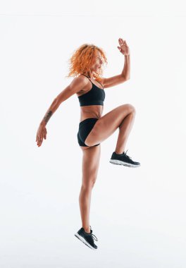 Egzersiz yapıyordum. Kızıl saçlı kadın vücut geliştirici beyaz arka planda stüdyoda..